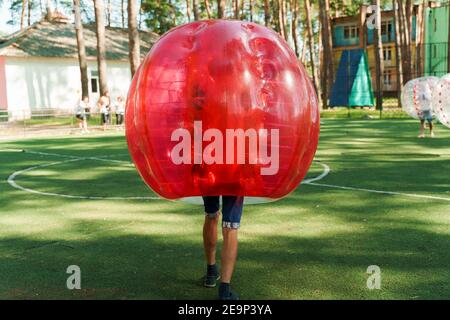 Bubble Fußball Sport Spiel. Fußballspieler spielen Bumperball auf dem grünen Feld. Teambildung. Mann in Blase Ballon laufen. Stockfoto