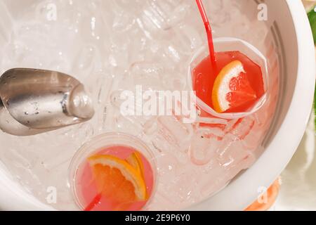 Eiscocktails und bunte Limonaden mit Früchten im Bad voller Eiswürfel. Begrüßungsbereich mit Getränken Stockfoto