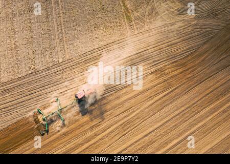 Luftaufnahme. Feld Für Das Pflügen Des Traktors. Beginn Der Landwirtschaftlichen Frühjahrssaison. Grubber gezogen von EINEM Traktor auf dem Land ländliche Feldlandschaft. Staub Stockfoto