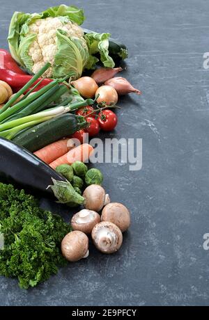 Frisches Gemüse wie Pilze, Karotten, Blumenkohl und mehr auf dunkelgrauem Schiefergrund, gesunde Ernährung für Fitness und Ernährung, Copy Space, vertica Stockfoto