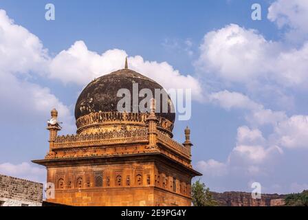 Badami, Karnataka, Indien - 7. November 2013: Nahaufnahme der roten Sonte Jamia Mashid oder Moschee geschwärzt durch Schimmel Kuppel unter blauer Wolkenlandschaft. Stockfoto