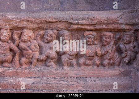 Badami, Karnataka, Indien - 7. November 2013: Höhlentempel über dem Agasthya See. Nahaufnahme der restone Skulptur der Reihe der kleinen menschlichen Figuren tanzen und Stockfoto