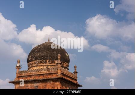 Badami, Karnataka, Indien - 7. November 2013: Nahaufnahme der roten Sonte Jamia Mashid oder Moschee geschwärzt durch Schimmel Kuppel unter blauer Wolkenlandschaft. Stockfoto