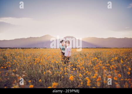 Ein Junge spricht mit einem anderen Jungen auf einem Wildblumenfeld In der Wüste Stockfoto
