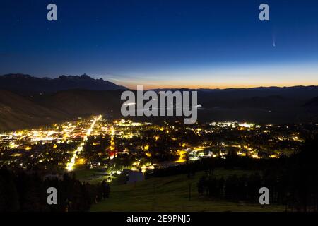 Komet Neowise streifend über der Stadt Jackson in den Stunden vor Sonnenaufgang des Tages, während nächtliche Wolken in der Ferne leuchten. Bridger-Teton Nation Stockfoto