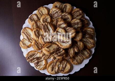 Blick von oben auf hausgemachte Blätterteig Palme mit Schokolade präsentiert In weißer Platte auf braunem Holztisch Stockfoto