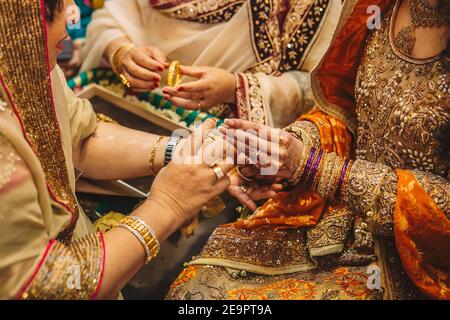 Schwiegermutter Hilfe für indische pakistanische Braut zu tragen goldener Schmuck Stockfoto