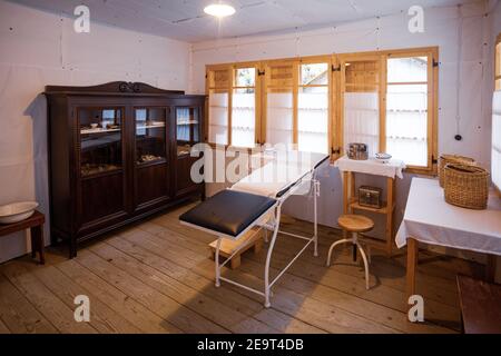 Eine alte Arztpraxis mit einem Arzttisch, Schrank, Stuhl und anderen medizinischen Hilfsgütern. Stockfoto