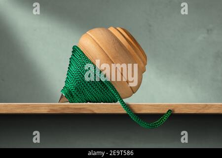 Nahaufnahme eines hölzernen Spinning Top mit einem grünen Seil, auf einem Holzregal und einer grünen Wand. Vintage-Spielzeug. Stockfoto