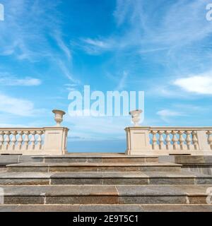 Nahaufnahme einer Marmortreppe und einer weißen Balustrade mit blauem Himmel und Wolken im Hintergrund. Stockfoto