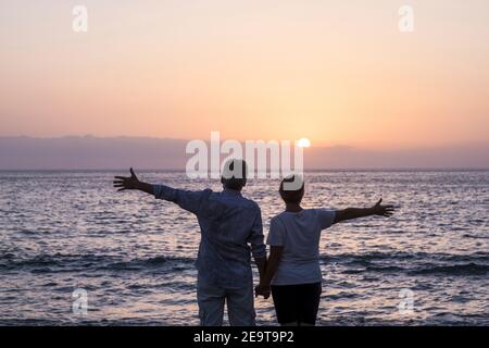 Glückliches Ehepaar Verliebte genießen einen Sonnenuntergang Der Ozean hält die Hände - ñpve und die Beziehung älterer Sommer Urlaub Lifestyle Mann und Frau zu Stockfoto