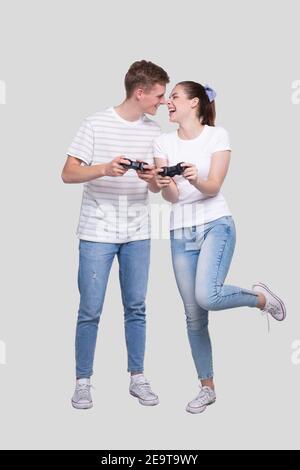 Pärchen steht mit Joysticks in den Händen und schaut einander an Verschmierend Isoliert Stockfoto