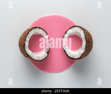 Kreatives Layout aus Kokosnuss in der Mitte mit rosa Milch Gießen. Minimales Lebensmittelkonzept. Stockfoto