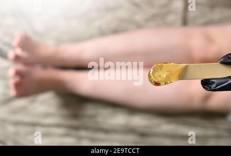 Zuckerpaste zum Shugaring auf dem Hintergrund der weiblichen Beine. Weibliche Enthaarung. Beauty und Hautpflege Konzept. Stockfoto