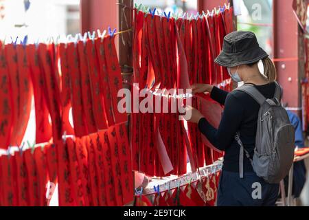 Hongkong, Hongkong, China. Februar 2021, 6th. Eine Dame nimmt einige von der Kalligrafie sifu (Meister) handgemalte Pappeln heraus, die an einer befahrenen Straße in Causeway Bay Hong Kong arbeiten und bereit für das chinesische Neujahr sind. Mondneujahrescouplets oder Cheun lyun, werden als Dekoration verwendet und haben unterschiedliche glückverheißende Nachrichten, die auf ihnen geschrieben werden. CNY wird am Freitag, 12th. Februar 2021 mit dem Feiertag beginnen, der das Tierkreisjahr des Ochsen ankündigt. Quelle: Jayne Russell/ZUMA Wire/Alamy Live News Stockfoto