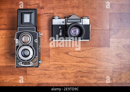 Eine alte Mittelformat-Spiegelreflexkamera und eine alte Spiegelreflexkamera 35mm, von oben gesehen horizontales Format mit Kopierraum Stockfoto
