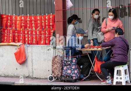 Hongkong, Hongkong, China. Februar 2021, 6th. Eine Kalligraphie sifu (Meister) arbeitet an der Seite einer belebten Straße in Causeway Bay Hongkong und produziert handbemalte kantonesische Couplets, die für das chinesische Neujahr bereit sind. Mondneujahrescouplets oder Cheun lyun, werden als Dekoration verwendet und haben unterschiedliche glückverheißende Nachrichten, die auf ihnen geschrieben werden. CNY wird am Freitag, 12th. Februar 2021 mit dem Feiertag beginnen, der das Tierkreisjahr des Ochsen ankündigt. Quelle: Jayne Russell/ZUMA Wire/Alamy Live News Stockfoto