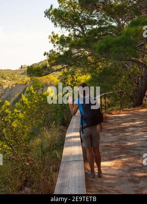 Eine Wanderin mit einem Backpacker, der mit ihrem Smartphone ein Foto vom Meer gemacht hat. Strunjan, Slowenien Stockfoto