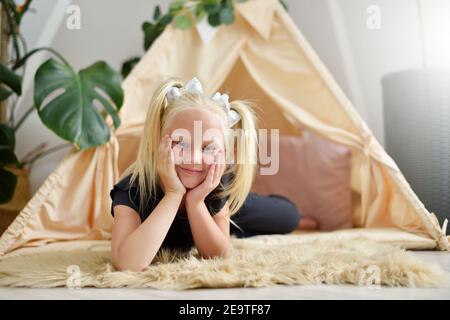 Kleines Mädchen mit einem Lächeln in ihrem Zimmer auf der Stock neben dem Wigwam Zelt Stockfoto