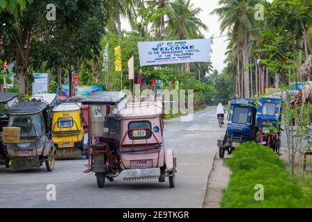 Eine Straße mit Motorradtaxis und einem Walhai-Banner über dem Kopf, in Donsol, Sorsogon Province, Luzon, Philippinen. Stockfoto