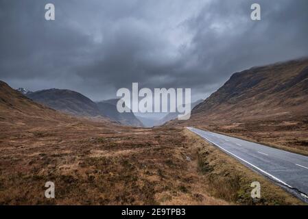 Atemberaubende Landschaftsaufnahme im Glencoe Valley in den schottischen Highlands Mit Bergketten in dramatischer Winterbeleuchtung Stockfoto