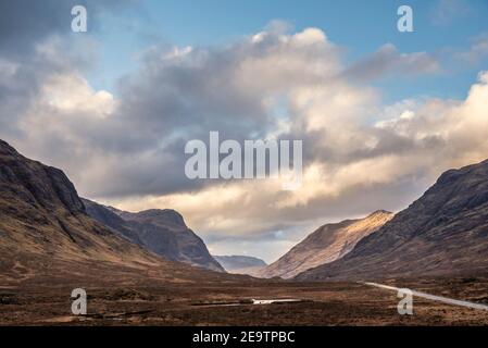 Atemberaubende Landschaftsaufnahme im Glencoe Valley in den schottischen Highlands Mit Bergketten in dramatischer Winterbeleuchtung Stockfoto