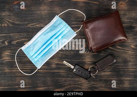 Draufsicht auf medizinische Maske, Schlüssel und Brieftasche auf einem Tisch platziert. Wesentliche Elemente während der Epidemie covid19. Stockfoto