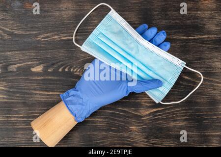 Schaufensterpuppe Hand trägt einen Einweghandschuh und hält eine medizinische Maske. Während der Quarantäne von covid19. Stockfoto