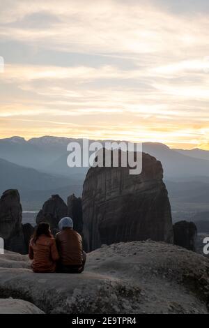 Ein Paar sitzt und genießt die Aussicht von einem der Meteora Felsen. UNESCO-Weltkulturerbe Meteora, Griechenland Stockfoto