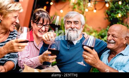 Glückliche ältere Freunde, die beim Abendessen gerne Rotwein toasten Party - Rentner trinken im Restaurant zusammen - Essen Freundschaftskonzept Stockfoto