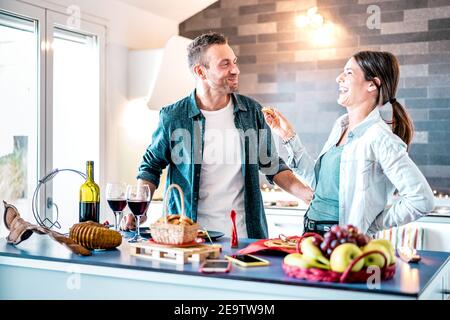 Junges Paar in der Liebe mit Spaß am Haus Küche - Glückliche Jahrtausendeliebhaber genießen gemeinsam zu Hause am Jubiläum das Mittagessen Jahrestag