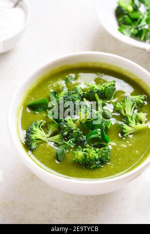 Gesunde Brokkoli grüne Erbsencremesuppe in Schüssel über hellem Stein Hintergrund. Diät Detox Food Konzept. Nahaufnahme Stockfoto