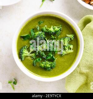 Nahaufnahme der gesunden Brokkoli grüne Erbsencremesuppe in der Schüssel. Diät Detox Food Konzept. Draufsicht, flach liegend Stockfoto