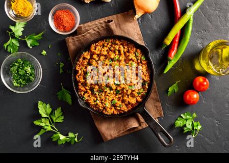 Keema Curry in Bratpfanne auf schwarzem Stein Hintergrund. Indische und pakistanische Gerichte. Draufsicht, flach liegend Stockfoto