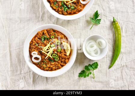 Keema Curry in Schüssel über hellem Hintergrund. Indische und pakistanische Gerichte. Draufsicht, flach liegend Stockfoto