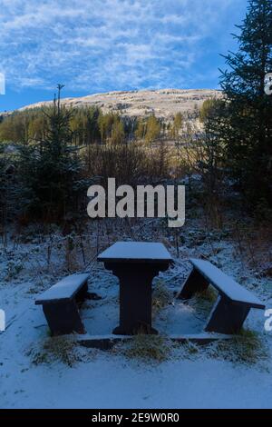 Schneebedeckte Picknickbänke auf einem Bergspaziergang in Schottland Stockfoto