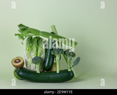 Frisches grünes Gemüse und Obst auf grünem Hintergrund. Gleichgewicht schwimmende Lebensmittelbalance. Stockfoto