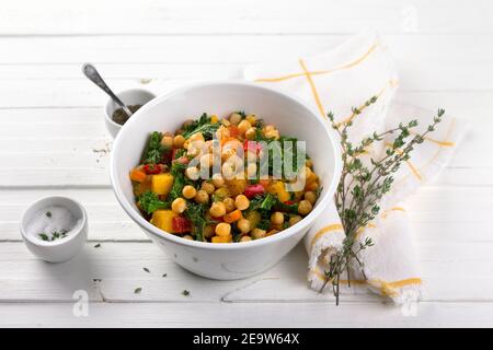 Hausgemachtes Ragout mit Kürbis, Karotten, Paprika, Tomaten, Kichererbsen, Grünkohl und Thymian in einer weißen Schüssel auf weißem Hintergrund. Lecker gesundes Foo Stockfoto