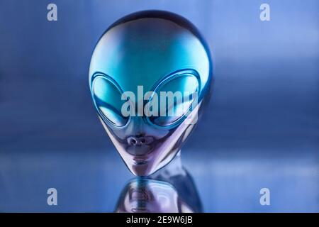 Alien Metall Kopf Statue auf blauem Hintergrund auf dem Tisch Stockfoto