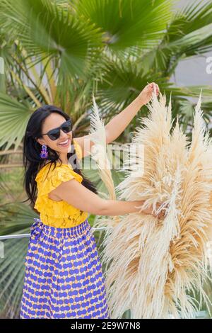 Nette lateinische Frau genießt die Anordnung ihrer Pampas Gras Blumenarrangement Stockfoto