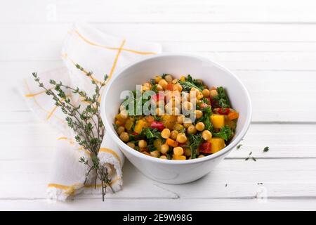 Hausgemachtes Ragout mit Kürbis, Karotten, Paprika, Tomaten, Kichererbsen, Grünkohl und Thymian in einer weißen Schüssel auf weißem Hintergrund. Lecker gesundes Foo Stockfoto