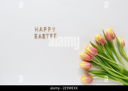 Ostern Grußkarte Vorlage mit Happy Easter Text und Tulpen auf weißem Hintergrund, minimale Zusammensetzung, flach liegend, Blick von oben, Kopierraum Stockfoto