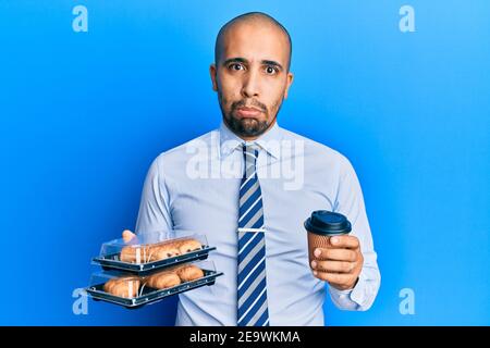 Hispanic erwachsenen Geschäftsmann hält Take Away Kaffee und Süßigkeiten deprimiert und sorgen für Not, Weinen wütend und Angst. Trauriger Ausdruck. Stockfoto