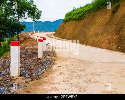 Atemberaubende Schotterstraße mit rot-weißen Pfählen markiert, Klettern die Berge von Sapa, berühmt für seine terrassenförmig angelegten Reisfelder, Nordvietnam Stockfoto