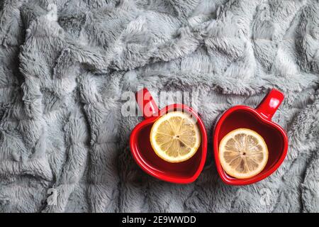 Zwei warme Getränke und eine Decke. Herz Form Tee Tasse als Liebe oder Valentinstag Symbol. Zitronentee im Becher Stockfoto