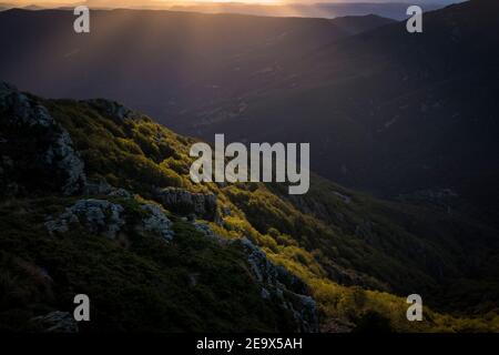 Bewaldete Hügel mit Lichtwellen, die durch Wolken kommen. Naturpark Montseny. Katalonien. Spanien. Stockfoto