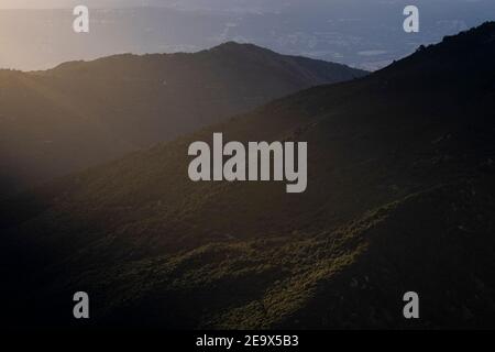 Bewaldete Hügel mit Lichtwellen, die durch Wolken kommen. Naturpark Montseny. Katalonien. Spanien. Stockfoto