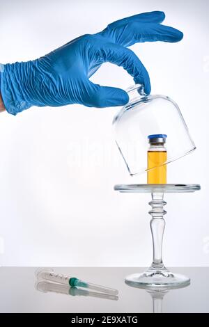 Covid-19 Impfstoffpräsentationskonzept, Vials-Impfstoffdosis in Glasklöche und Spritze auf Spiegelfläche, weißer Hintergrund, selektiver Fokus Stockfoto