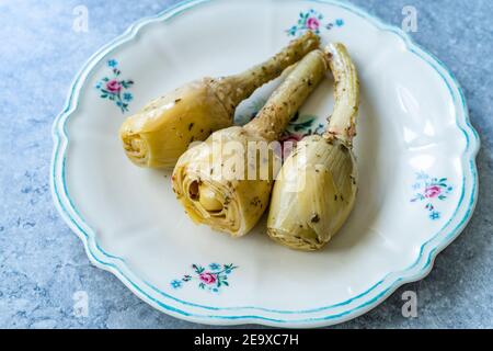 Marinierte würzige Artischockenherzen in Olivenöl serviert mit Wurzel. Bereit zum Essen. Stockfoto