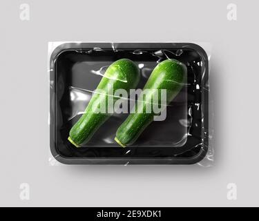 Lebensmittelverpackung isoliert mit Zucchini Draufsicht Mockup Platte für Designer. Frische grüne Zucchini mit Scheibe isoliert auf weißem Hintergrund. Stockfoto